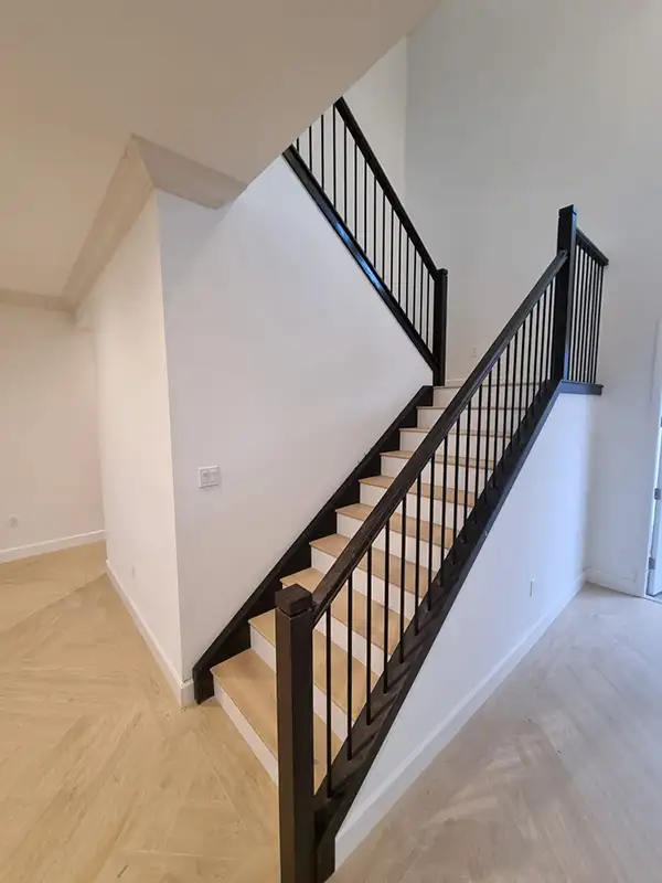 Staircase with black metal railing and new flooring